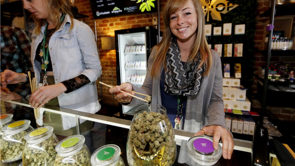 In this Friday, Dec. 18, 2015, photograph, LivWell store manager Carlyssa Scanlon shows off some of the products available in the marijuana line marketed by rapper Snoop Dogg in one of the marijuana chain's outlets south of downtown Denver. LivWell grows the Snoop pot alongside many other strains on its menu. (AP Photo/David Zalubowski)