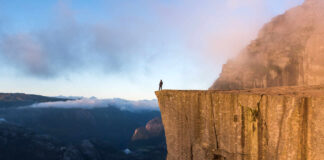 Nature Restoration Group – On the Precipice of Change, Stepping into Planetary Stewardship Human standing on the edge of a cliff on a misty morning.