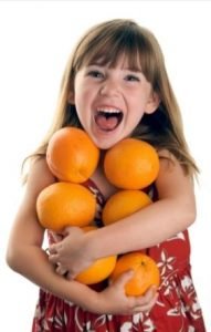 Little girl, arms full of oranges