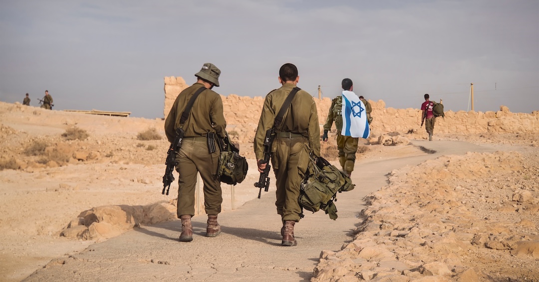 Back shot of several soldiers of israel army walking with israel national flag. Military man walking with other soldiers. War tactical exercise. infantry retreat from positions
